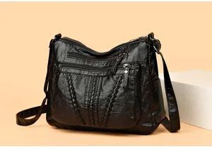 Black multi-zipper shoulder bag detail view showing soft leather and braided texture.