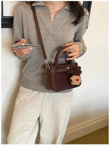 Retro brown shoulder handbag for women, commuter crossbody bag with cute bear pendant and strap.