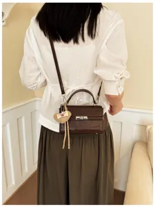 Retro brown top-handle crossbody bag with heart pendant for women, stylish daily commute square bag.