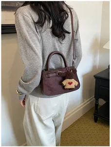 Retro suede shoulder bag for women, trendy commuting crossbody handbag with cute bear charm.