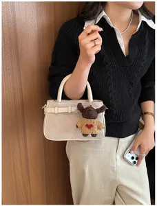 Detailed view of women's vintage suede handbag with cute bear keychain and belt design.