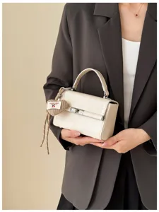 Elegant beige mini top handle bag with chic metal lock and cute knitted heart charm daily commute.