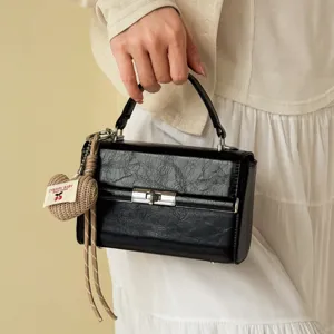 Black textured top handle handbag retro small square bag with cute knitted heart charm pendant.