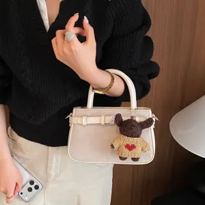 Chic retro women's handbag, stylish commuter shoulder bag with cute plush bear charm.