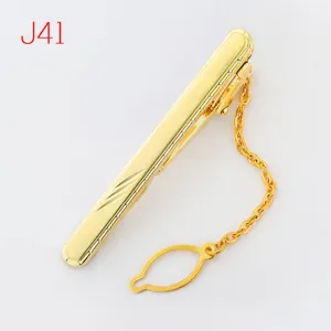 Gold metal tie clip detail shot featuring a classic chain and geometric pattern design.