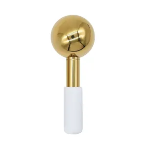 Gezichtsijskogel koelend schoonheidsmassagehulpmiddel detail, gouden bol met witte handgreep.