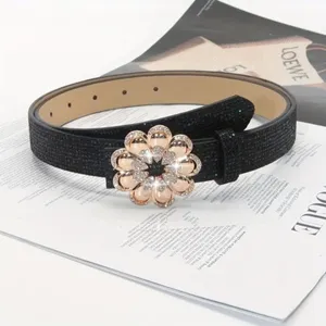 Detailed view of women black rhinestone flower buckle belt, sparkling fashion accessory.