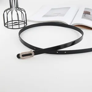 Gros plan de l'élégante fine ceinture en cuir noir avec sa boucle ovale en strass scintillants.