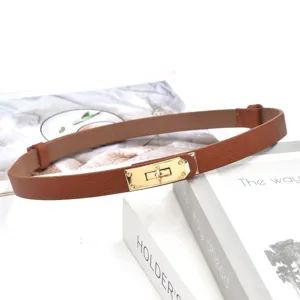 Detailopname van bruine smalle lederen riem met gouden metalen slotgesp voor dames.