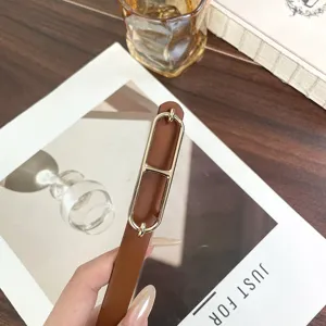 Close-up of a stylish brown thin leather belt with a gold-tone metal buckle, detail view.