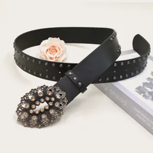 Detailed view of a vintage black leather belt with rhinestone carved buckle and metal rivets.