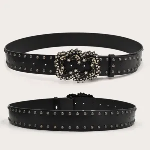Detailed view of black studded punk belt with sparkling rhinestone ornate buckle, close-up shot.