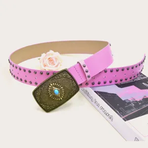 Pink studded leather belt detail with vintage engraved brass buckle and turquoise stone decor.