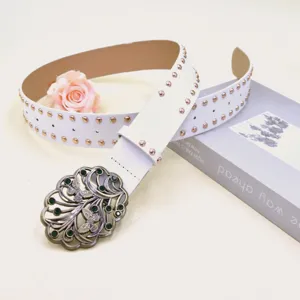 Detailed view of white punk rivet wide belt with ornate vintage butterfly metal buckle closeup.