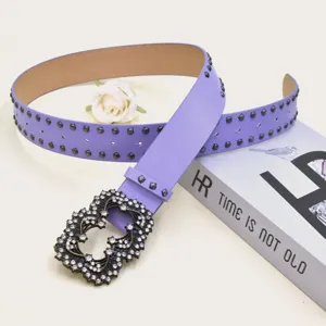 Detail shot of a stylish purple leather belt with metal studs and sparkling rhinestone buckle.