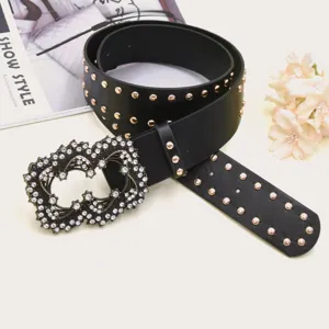 Close-up of black leather punk style wide belt with metal rivets and rhinestone buckle.