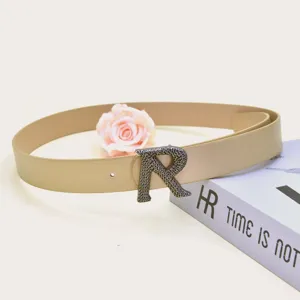 Detail shot of stylish PU leather belt with metallic R buckle, elegant fashion accessory.