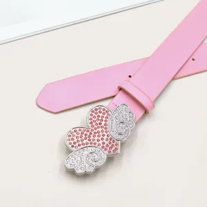 Nahaufnahme des rosa Ledergürtels mit funkelnder Strass-Herz-Flügel-Schnalle im Detail.