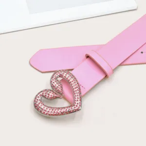 Nahaufnahme des rosa Ledergürtels mit einer funkelnden Strass Herz Metallschließe Detail.