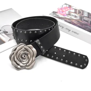 Détail de la ceinture en cuir noir style punk avec rivets métalliques et boucle rose vintage.