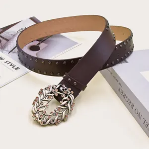 Detailed view of women retro brown leather belt with floral rhinestone buckle and metal studs.