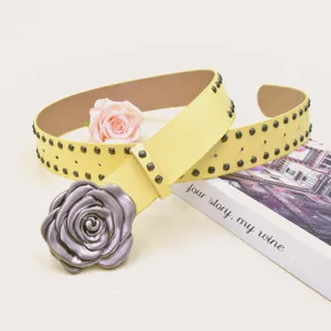 Vue détaillée de la ceinture en cuir jaune punk avec grande boucle de rose vintage et rivets.
