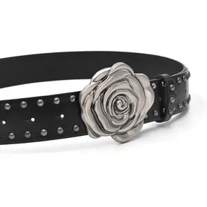 Gros plan sur la ceinture en cuir noir avec boucle rose argentée et clous en métal.