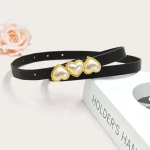 Dettaglio cintura sottile nera con eleganti fibbie a cuore di perla per abiti da donna.