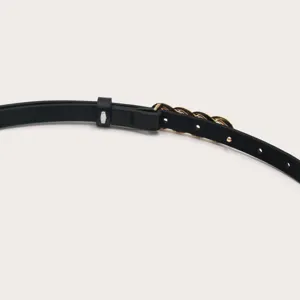 Detailopname van de elegante zwarte dunne lederen riem met gouden kettinggesp en gaatjes.