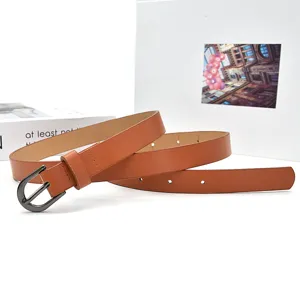 Detailfoto van een minimalistische bruine leren damesriem met een donkere metalen gesp.