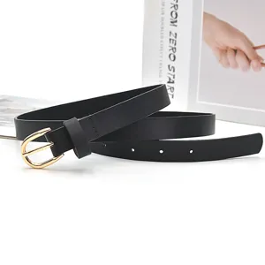 Close-up of black thin leather belt with gold metal buckle, elegant fashion accessory detail.