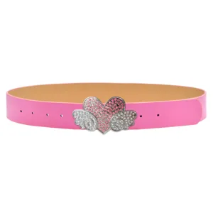 Dettaglio ravvicinato della cintura rosa con fibbia scintillante a cuore e ali in strass.