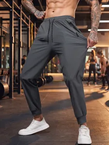 Detailed view of men's quick-dry athletic joggers featuring elastic waist and zip pocket.
