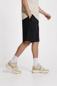 Vista de cerca de los pantalones cortos deportivos negros con detalle de bolsillo y ajuste.