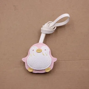Gros plan détaillé du joli pendentif pingouin en cuir rose et blanc avec lanière blanche.