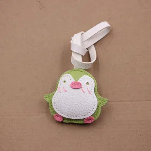 Gros plan du joli charm de sac pingouin en cuir fait main avec lanière blanche.