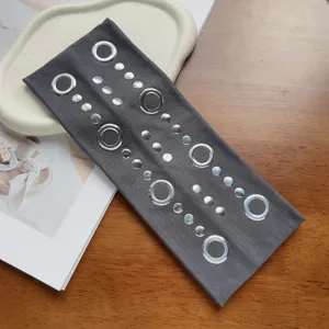 Gros plan détaillé du bandeau en tissu gris style punk avec anneaux métalliques et clous.
