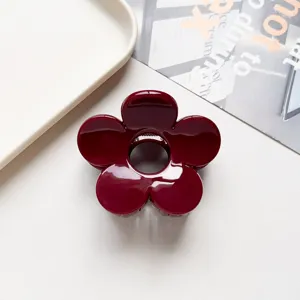 Detail shot of a glossy burgundy flower hair claw clip, cute shark clip for half updo styling.