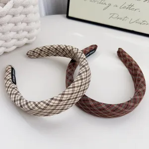 Vue détaillée de cerceaux à cheveux éponge à carreaux marron, accessoire de coiffure chic.