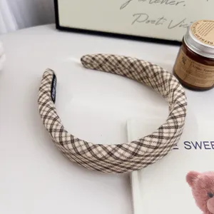 Détail de serre-tête à carreaux marron, design haut, accessoire de cheveux en tissu doux.