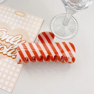 Detailed view of a stylish orange and white striped PVC hair claw clip, minimalist design.