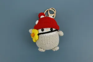 Portachiavi in peluche pinguino all'uncinetto fatto a mano con cappello fungo rosso.