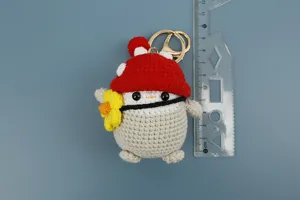 Vista dettagliata di un peluche pinguino all'uncinetto fatto a mano con cappello a fungo.