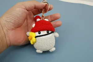 Vista dettagliata del portachiavi pinguino all'uncinetto fatto a mano con cappello fungo rosso.