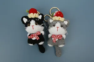 Vue détaillée du porte-clés en peluche chat au crochet fait main avec chapeau de fraise.