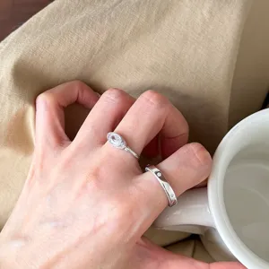 Gros plan détaillé de bagues en argent empilées élégantes portées avec une tasse.