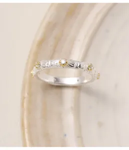 Gros plan détail d'une bague en argent marguerite avec des accents dorés et des pierres étincelantes.