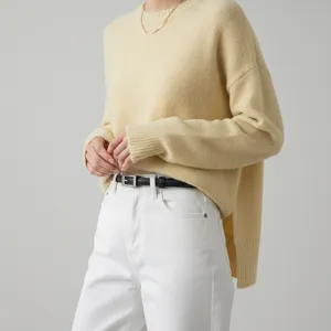 Detailed shot of a black thin leather belt paired with a stylish sweater and white jeans.