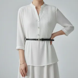 Detail shot of slim black leather belt with elegant metal buckle styled on white top.