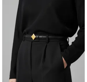 Womens slim black leather belt with gold geometric buckle, elegant accessory for trousers.